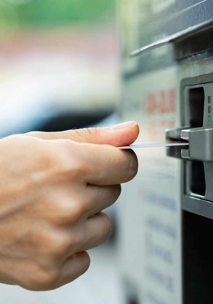 Closeup of female hand with a credit card and ticket vending machine